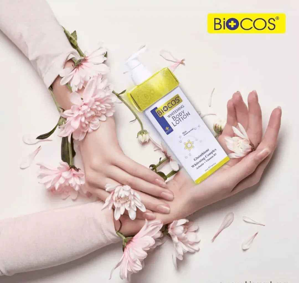 Biocos whitening body lotion bottle held in hands, gold cap and white pump