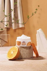 Vitamin C face cream jar with orange lid and citrus slices on display