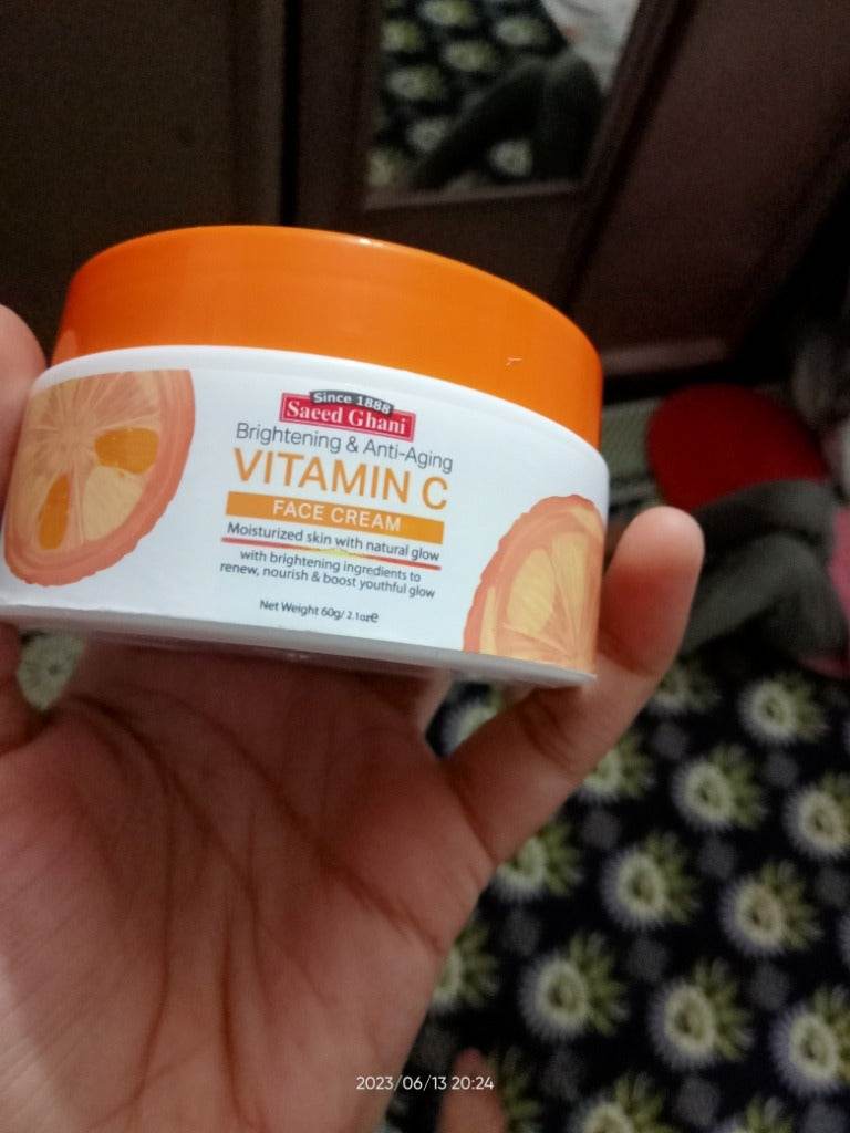 Vitamin C face cream jar in hand, showing label with citrus graphics